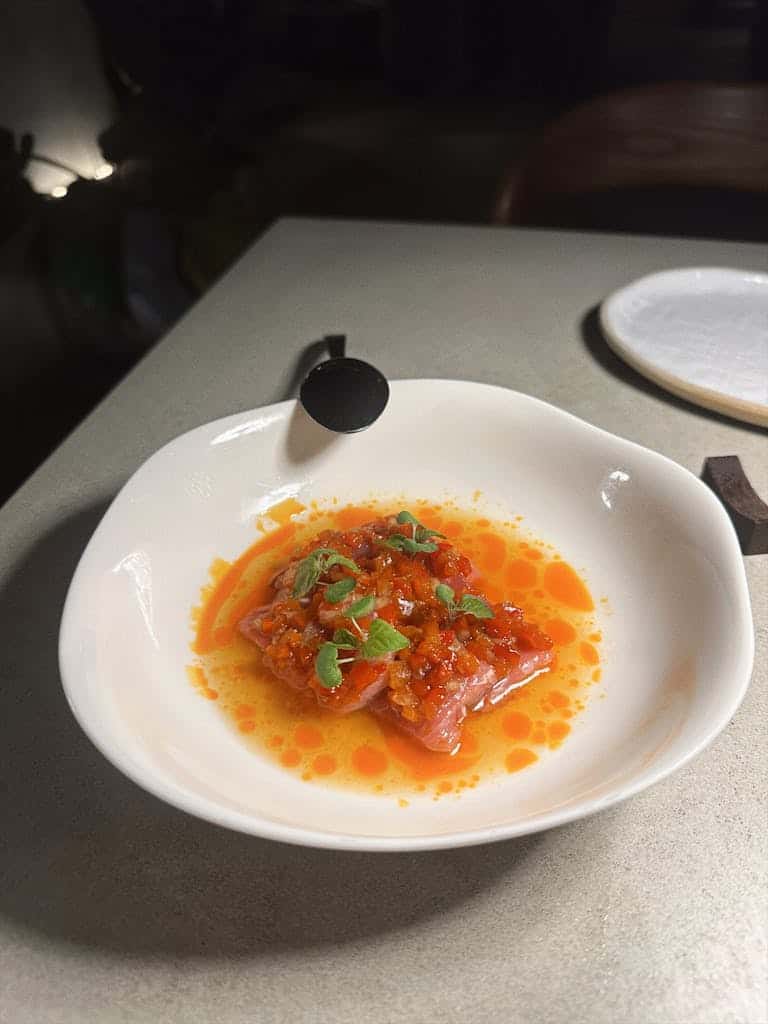 Delicious salmon tartare garnished with vibrant herbs in white dish.